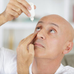 Man putting eye drops in eyes